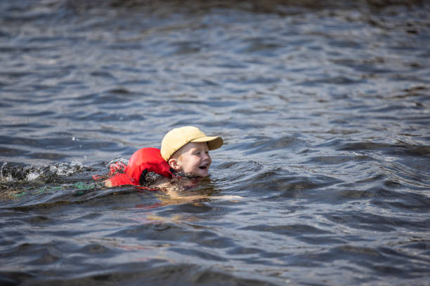 giovane ragazzo che nuota nel lago durante l'estate - life jacket little boys lake jumping foto e immagini stock