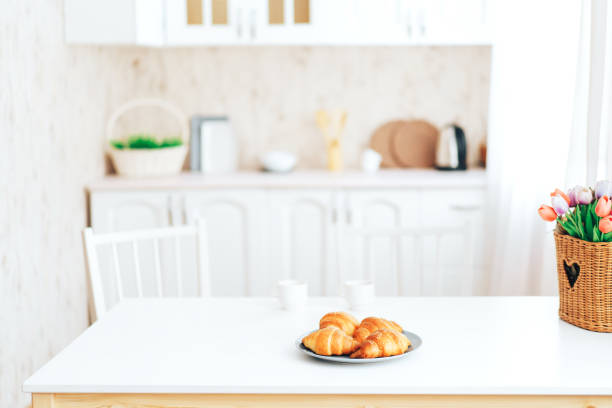 istock Croissants on wooden table in front of blurred kitchen 1367440347