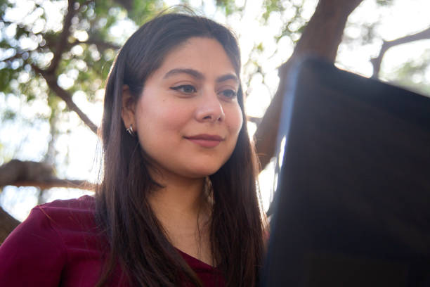 istock Young woman using laptop in the park 1367446643