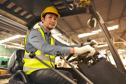 Engineer Man forklift driver with a background in an industrial or warehousing factory.