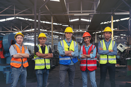 A group of industry workers and engineers of various races enjoy working in a heavy plant and stand together with a pleasant smile. portrait