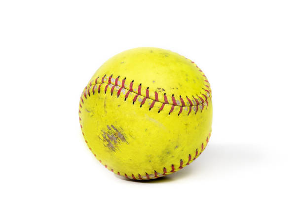 Used slowpitch softball, isolated Small ball used for team sports. Yellow durable leather or polyester material with red chevron stitching. Isolated on white. Selective focus. baseball isolated on white stock pictures, royalty-free photos & images