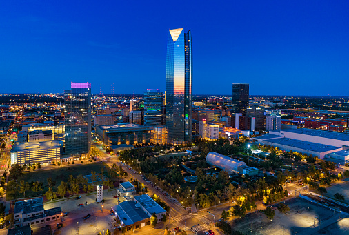 Downtown Oklahoma City skyline aerial view at dusk with a reflection of the sunset on the Devon Energy Center in the middle, and Myriad Botanical Gardens in the foreground.