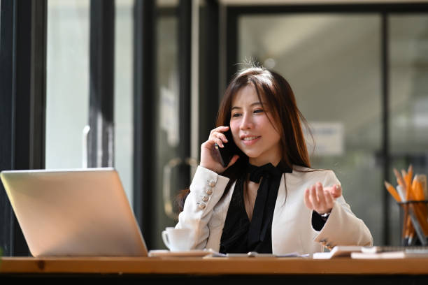 istock Attractive business woman talking on smart phone and working with laptop computer. 1367461852