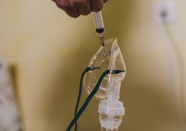 istock Closeup of a hand with a syringe preparing a compressor nebulizer for inhaling treatment 1367464537