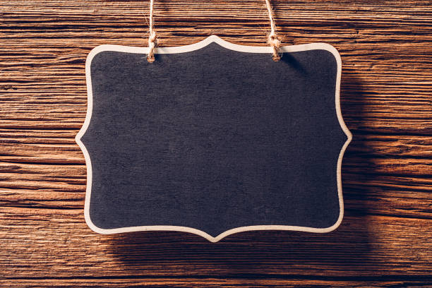 istock Empty black chalkboard sign hanging on rope on wood background 1367472865