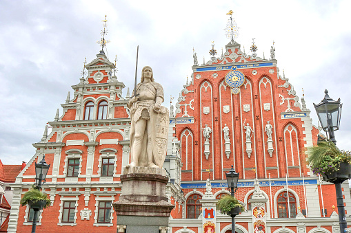 The House of the Blackheads and the statue of Roland in the center of the old town of Riga - colorful postcard of the capital of Latvia with a cloudy background