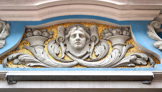 facade with relief in art nouveau style, with a female head and a golden mosaic on a blue background