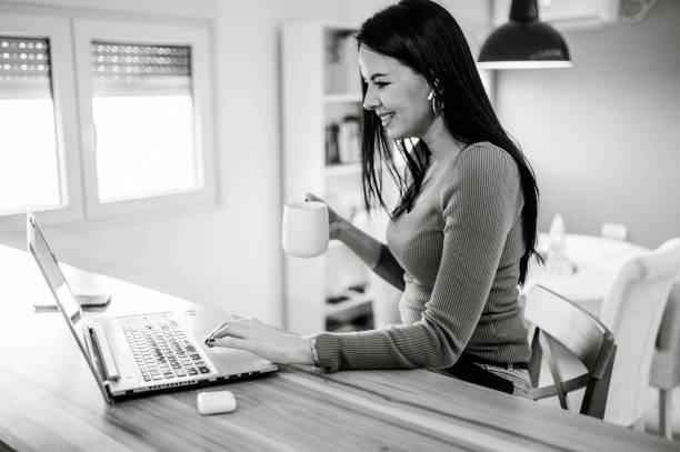 istock Middle aged woman drinking morning coffee and using a laptop at home 1367475467