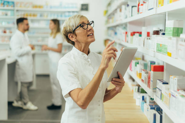 istock Beautiful senior female pharmacist checking medications on a shelf 1367475504