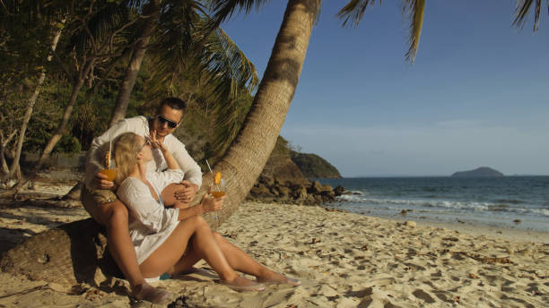 Loving couple in white dress and sunglasses, near palm tree, rel stock photo