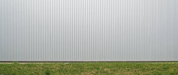 parede exterior de armazém feito de folha de alumínio ondulado e prado verde como imagem de fundo. - warehouse corrugated two dimensional shape distribution warehouse - fotografias e filmes do acervo