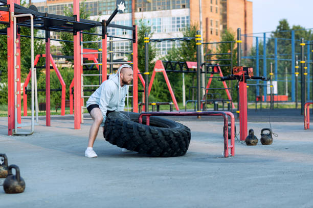 istock A man with a beard and interesting hairstyle does the tire press exercise (edging a heavy big tire) 1367482183