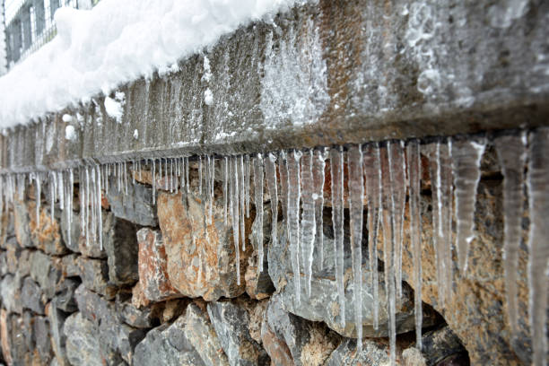 Bright, vivid and colorful background of icicles hanging from the rim of the roof. The spring or winter background of melting ice and snow in the sunny day