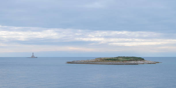 istock Small rocky islands with rocky shore in foreground and lighthouse in background 1367488083