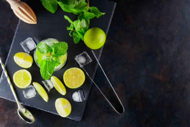 istock Mojito cocktail and ingredients on a dark background. Refreshing cocktail mojito on a slate board. Summer cocktail concept with lime and mint. Top view 1367489278