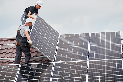 Hombre trabajador montando paneles solares en el techo de la casa. photo