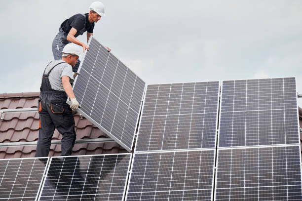 Man worker mounting solar panels on roof of house. Men technicians mounting photovoltaic solar moduls on roof of house. Builders in helmets installing solar panel system outdoors. Concept of alternative and renewable energy. solar energy stock pictures, royalty-free photos & images