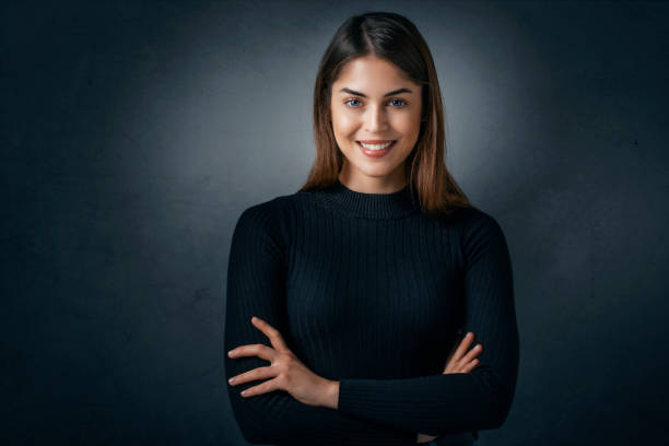 istock Confident young woman looking at camera and smiling while standing at isolated dark background 1367493121