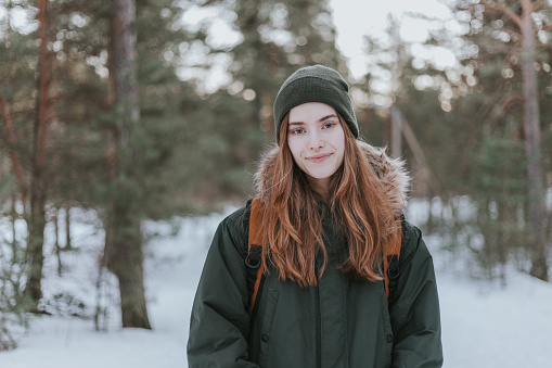 Portrait of positive young woman on a winter hike in forest.