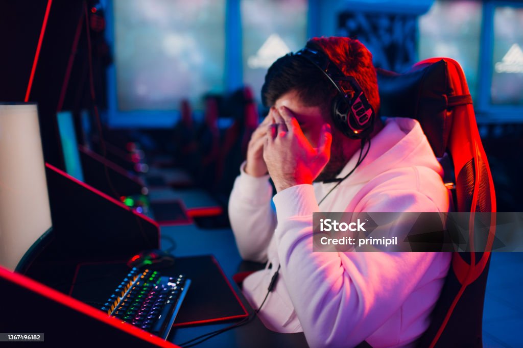Guy playing gaming game on computer at game club Guy Young man noob newbie gamer loss playing gaming game on computer at game club. Gamer Stock Photo