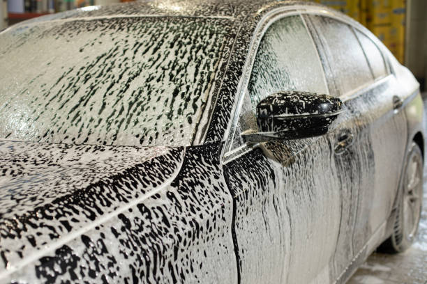 Car in car wash. Foam on car. White soapy solution. Cleaning of transport. stock photo