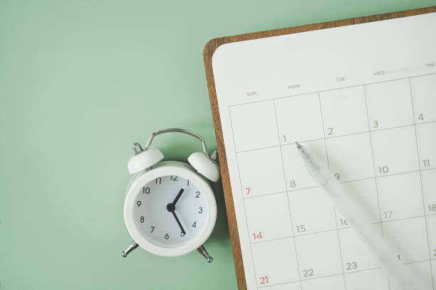 istock white pen on blank white planner and analog alarm clock on green background, top view 1367502358