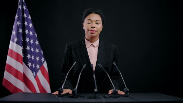 Calm black female official smiling at press conference listening debate opponent