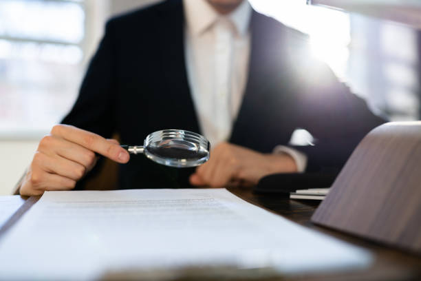 istock Lawyer Examining Paper Using Magnifier Glass 1367507421