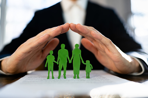 Cropped Image Of Businessman Covering Paper Family At Wooden Table