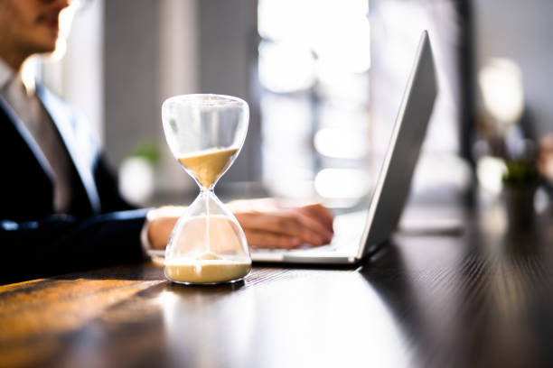 istock Hourglass On Desk. Running Late With Invoice 1367507682