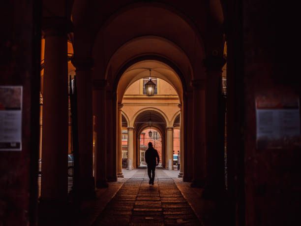 Silhouette of a person walking through the archways of Bologna, Italy stock photo