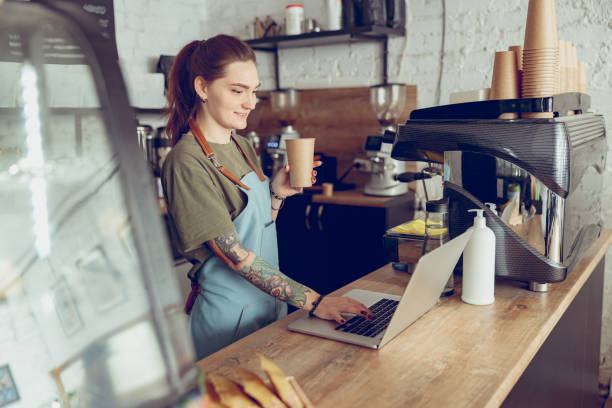 istock Smiling female barista using notebook in coffee shop 1367510978