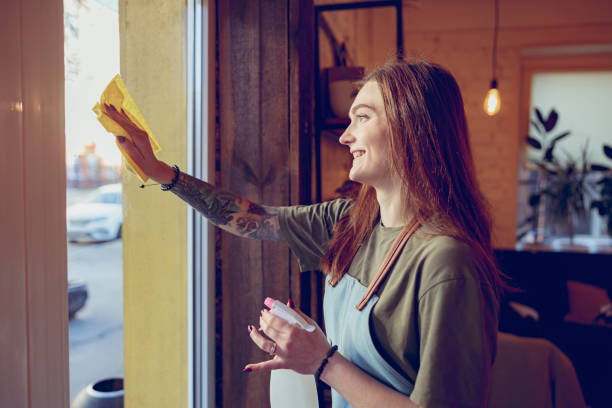 istock Cheerful young woman cleaning window on cafeteria 1367511023
