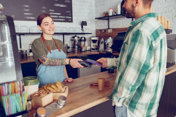istock Young man paying for coffee with smartphone in cafe 1367511035