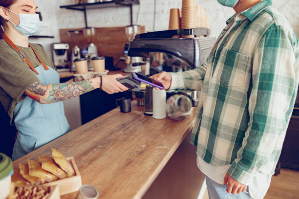 istock Man using smartphone to pay for coffee in cafeteria 1367511043