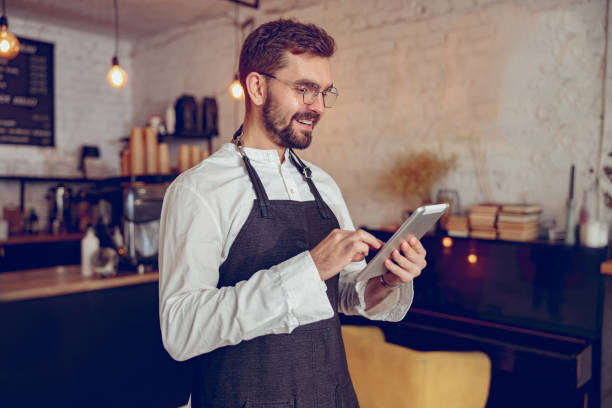 istock Joyful male barista using tablet computer in coffee shop 1367511072