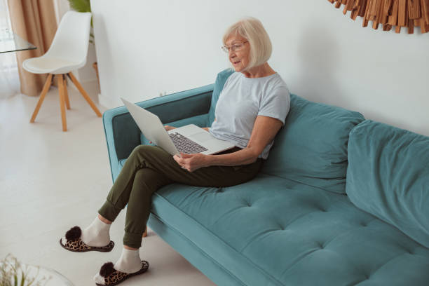 istock Senior woman using laptop while sitting at home 1367511569