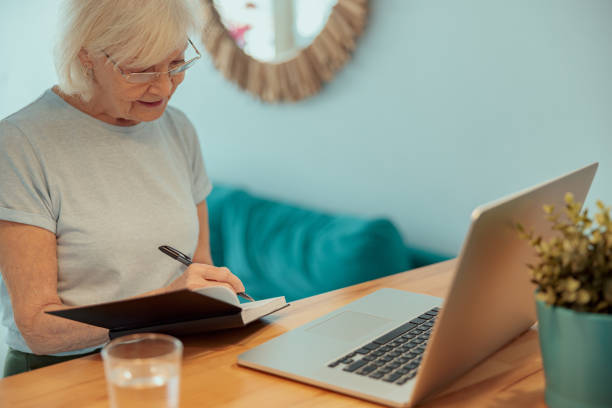 istock Beautiful older lady taking notes at home 1367511589
