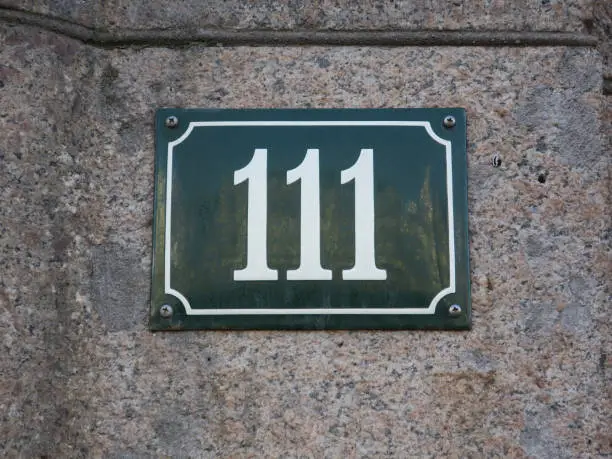 the housenumber 111 on an enamel sign on a stone wall