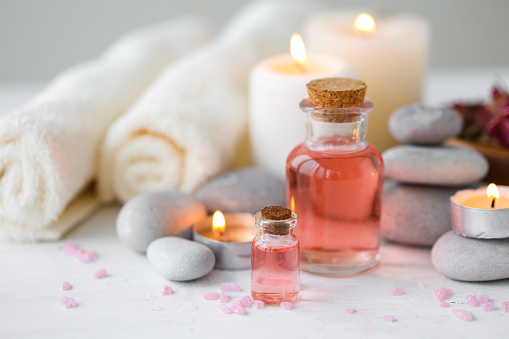 Concept of spa treatment in salon. Natural organic oil, towel, candles as decor. Atmosphere of relax, serenity and pleasure. Anti-stress and detox procedure. Luxury lifestyle. White wooden background