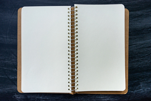 Blank open spiral notebook on blackboard