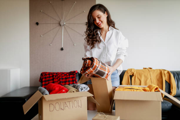 Woman sorting clothing and packing donation box Woman sorting clothing and packing donation box clothing donation stock pictures, royalty-free photos & images