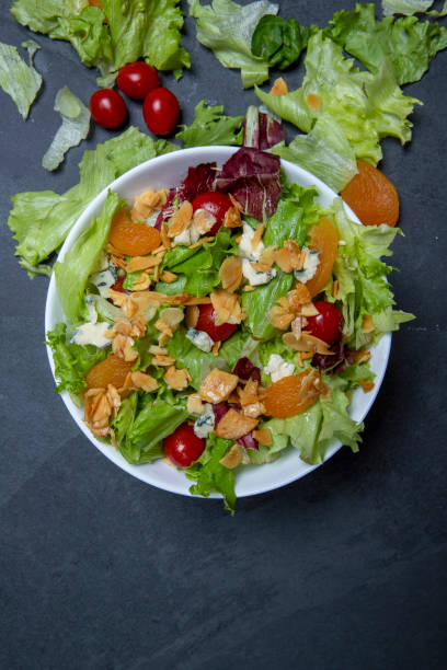 istock Salad on white plate, on black stone table. Space for text 1367514223
