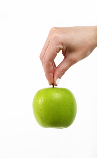 istock Woman hand holds green apple over white 1367517196