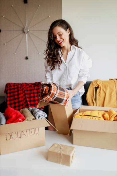istock Woman sorting clothing and packing donation box 1367518393