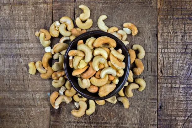 Ceramic bowl with cashew nuts, Anacardium occidentale, on a rustic wooden table. Brazil