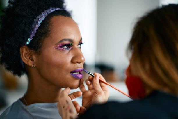 Mid adult black woman woman putting on make-up for Mardi Gras festival celebration. African American woman getting prepared for Mardi Gras carnival party. samba dancing stock pictures, royalty-free photos & images