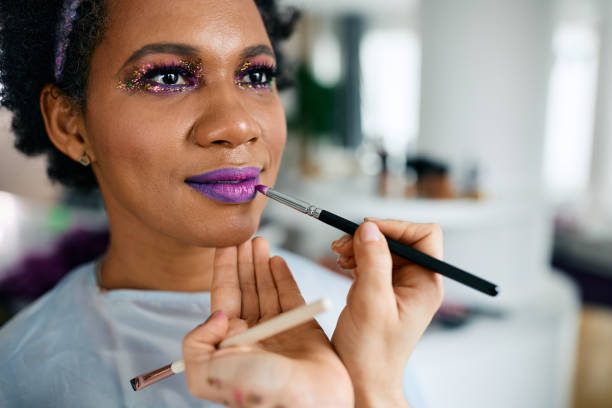 Close-up of African American woman getting ready for Mardi Gras party. Close-up of African American woman preparing for Mardi Gras celebration festival. mardi gras body painting stock pictures, royalty-free photos & images