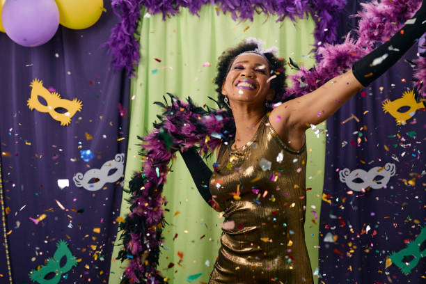 Carefree black woman celebrating Mardi Gras and dancing. African American woman having fun while dancing among confetti on Mardi Gras party. mardi gras confetti stock pictures, royalty-free photos & images